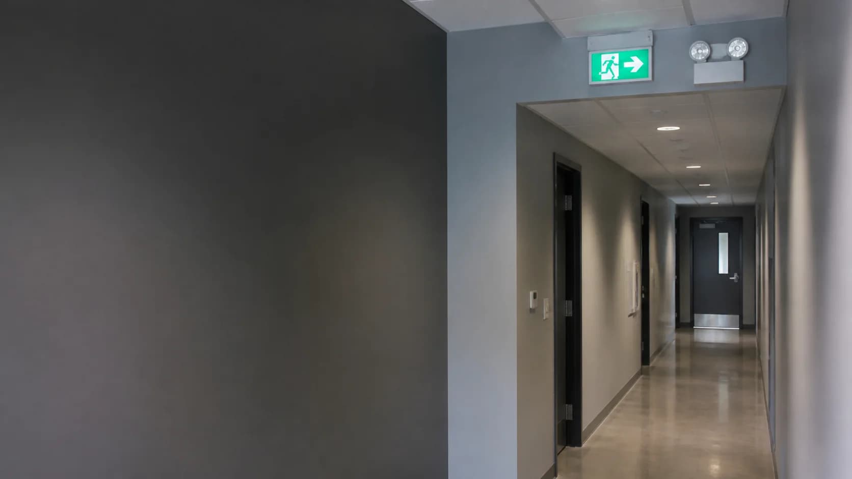 Commercial corridor with an illuminated exit sign and emergency lighting equipment